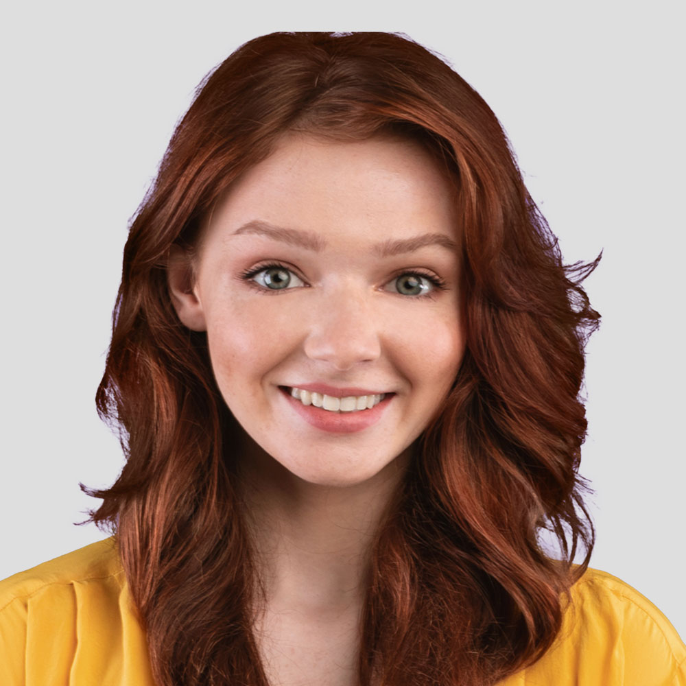 Femme aux cheveux roux souriant face à l'objectif